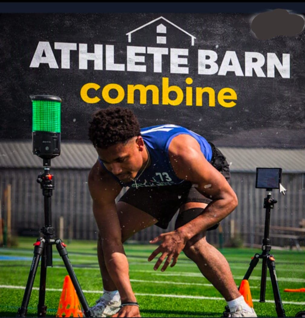 Athlete in a three-point stance at the start line of an Athlete Barn combine sprint, flanked by timing lights